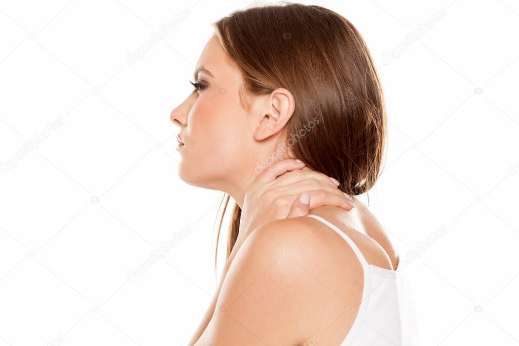 Beautiful girl with pain in her neck on white background