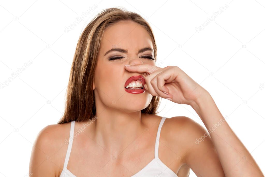 A young woman has itching in the nose on white background