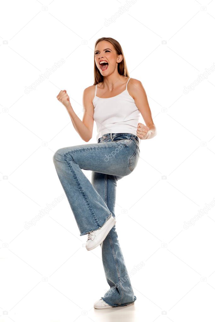 Happy young pretty woman posing in bell bottom jeans on white background