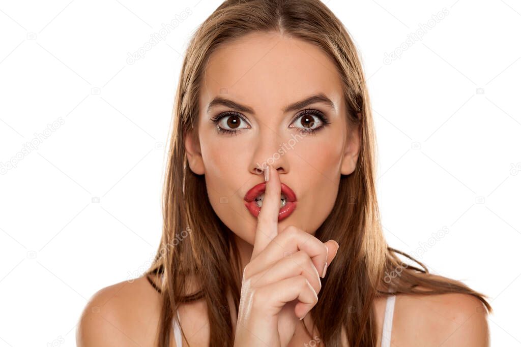 Beautiful girl with finger over her lips on white background