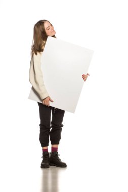 Genç model beyaz arka planda boş bir reklam panosu gösteriyor