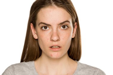 Beyaz arka planda makyajsız genç, ciddi bir kadın.