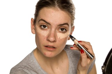 Beyaz arka plana kapatıcı süren genç bir kadın.