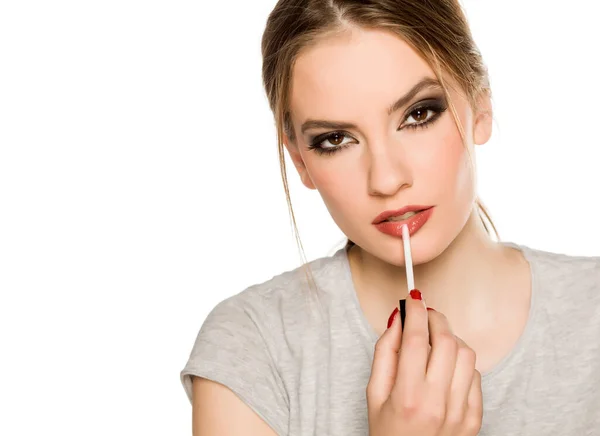 Mujer Joven Aplicando Brillo Labial Sobre Fondo Blanco — Foto de Stock