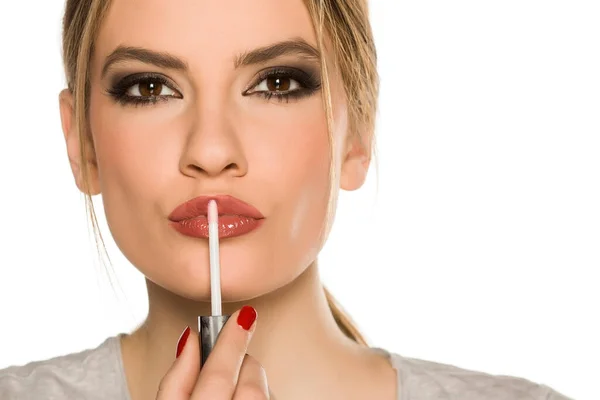 Mujer Joven Aplicando Brillo Labial Sobre Fondo Blanco — Foto de Stock