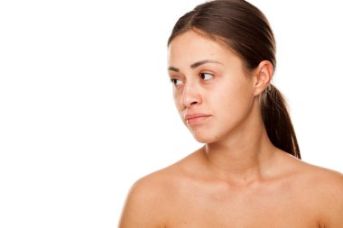 Beyaz arka planda makyajı olmayan güzel, üzgün bir kadının portresi.