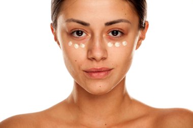 Yüzünde nemlendirici beyaz arka planda güzel bir kadın.