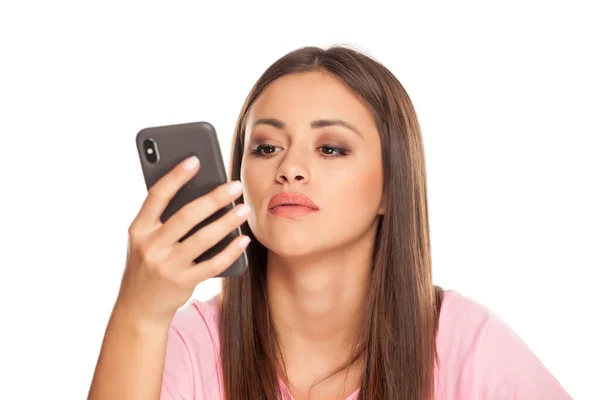 Mujer Joven Pensativa Mira Teléfono Inteligente Sobre Fondo Blanco — Foto de Stock