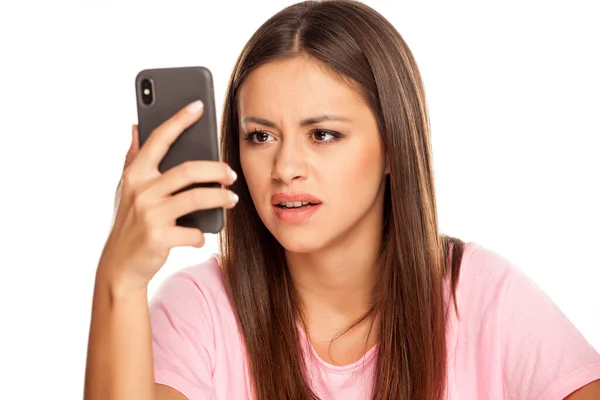 Mujer Joven Insatisfecha Mira Teléfono Inteligente Sobre Fondo Blanco — Foto de Stock