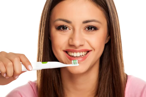 白い背景に電動歯ブラシで歯を磨く若い女性は — ストック写真