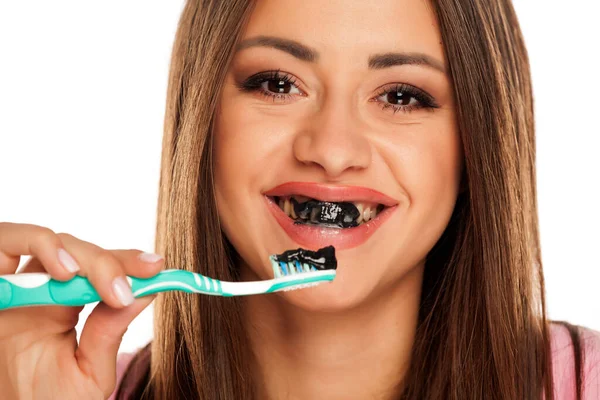 Молода Жінка Чистить Зуби Чорною Активною Вугільною Пастою Білому Тлі — стокове фото