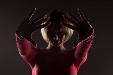 Elleriyle dur işareti gösteren bir sarışının silüeti.