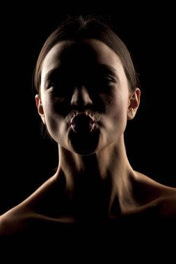 Siyah arka planda öpücük hareketi yapan bir kadının silueti.