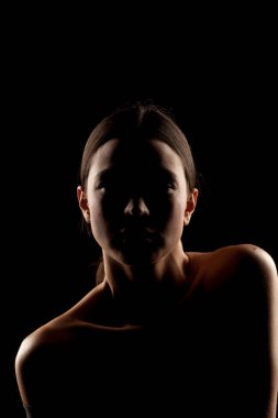 Siyah arka planda çıplak omuzlu bir kadının silüet portresi.