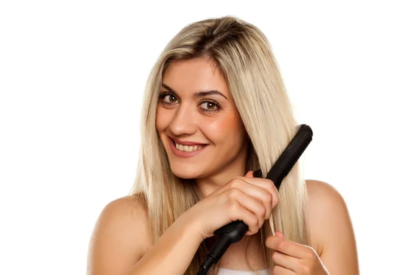 Sorrindo Jovem Mulher Engomando Seu Cabelo Com Ferro Cabelo Fundo — Fotografia de Stock