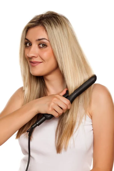 Lächelnde Junge Frau Bügelt Ihr Haar Mit Haarbügeleisen Auf Weißem — Stockfoto