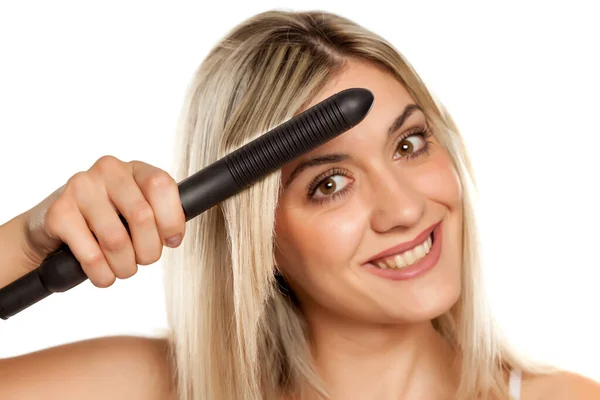 Sorrindo Jovem Mulher Engomando Seu Cabelo Com Ferro Cabelo Fundo — Fotografia de Stock