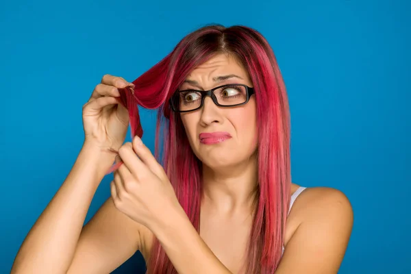 Mulher Infeliz Olhando Seu Cabelo Rosa Fundo Azul — Fotografia de Stock