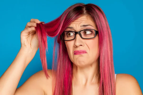 Нещаслива Жінка Дивиться Своє Рожеве Волосся Синьому Фоні — стокове фото