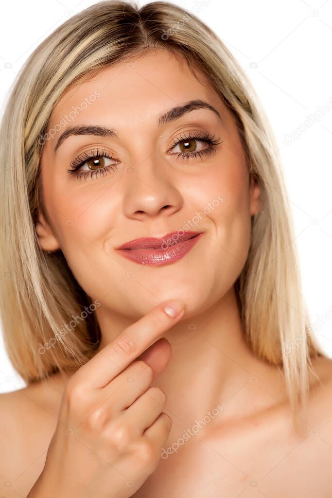Portrait of young blond woman, touching her chin on white background