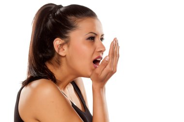 Güzel genç bir kadın beyaz arka planda ağız kokusunu kontrol ediyor.