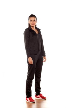 Stüdyoda beyaz arka planda poz veren eşofmanlı güzel bir kadın.