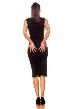 Dar siyah elbiseli, kalçasını tutan genç bir kadının arka görüntüsü.