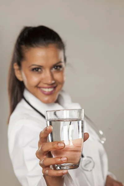 Mulher Sorridente Médico Segurando Copo Água Fundo Cinza — Fotografia de Stock