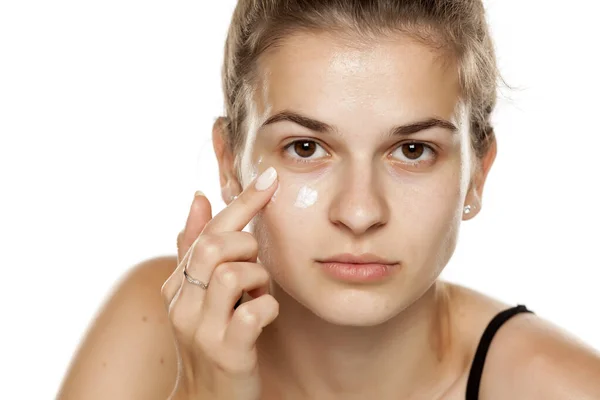 Mujer Joven Aplicando Crema Cara Sobre Fondo Blanco — Foto de Stock