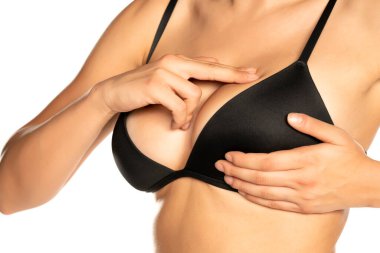 Kadın göğüslerini kontrol ediyor, parmakları beyaz arka planda.