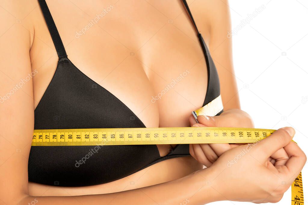 Woman measures her breasts with mettering tape