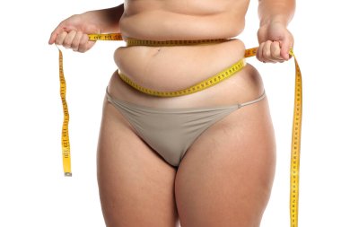 Obez kadının, kilo kaybı ve beyaz arka planda vücut ölçüsü için bant ile bel yağını sıkarkenki stüdyo fotoğrafı.