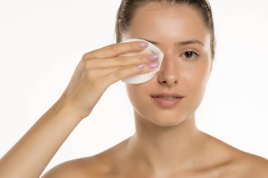 Makyajsız, beyaz arka planda pamuk yastıklı genç bir kadının stüdyo fotoğrafı.