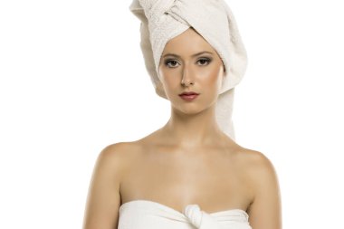 Havlu ve türbanlı zarif genç bir kadının stüdyo portresi. Makyajlı, kendinden emin ve ciddi görünüyor. Cilt bakımı, kaplıca, güzellik reklamları ve kozmetik markalar için mükemmel.