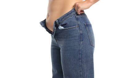 Beyaz arka planda göbek yağıyla dar kotları kapatmaya çalışan şişman kadının stüdyo fotoğrafı.