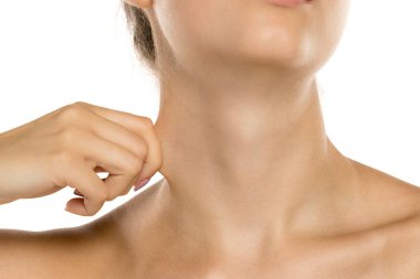 Stüdyo, beyaz arka planda parmaklarıyla derisini geren genç bir kadının yakın plan çekimini yaptı.