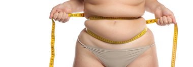 Beyaz arka planda diyet ve kilo kaybı konsepti için bant ölçüsüyle belini sıkan obez kadının stüdyo çekimi.