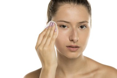 Makyajsız, beyaz arka planda pamuk yastıklı genç bir kadının stüdyo fotoğrafı.