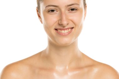 Beyaz arka planda ıslak tenli ve doğal görünüşlü gülümseyen genç bir kadının stüdyo fotoğrafı.