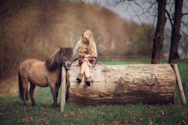 büyük günlük üzerinde oturan ve atını çiftlikte okşayarak beyaz kız 