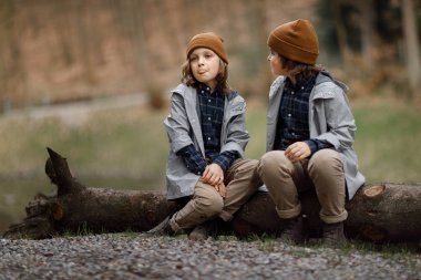 Ormanda büyük günlüğü üzerinde oturan kardeşi ile dil gösteren komik çocuk 