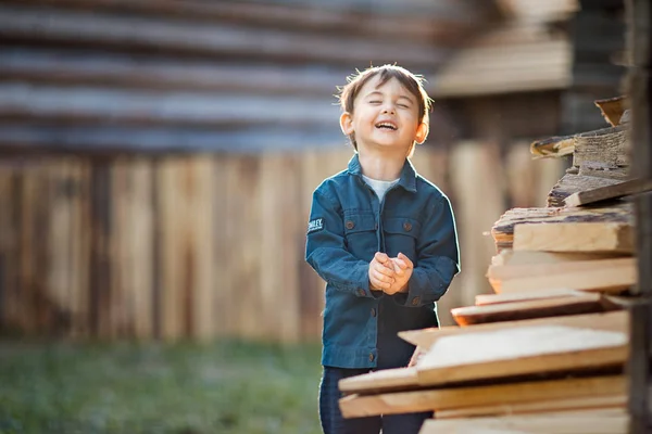 Vrolijke Jongen Staande Stapel Van Logboeken Met Onscherpe Achtergrond — Stockfoto