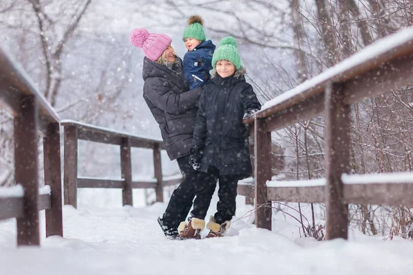 幸せな母の手に小さな息子と雪の公園でカメラを見て長男を保持 — ストック写真