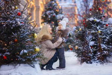 Anne ve kızı sokakta Noel ağaçları ile birbirine bakarak gülen