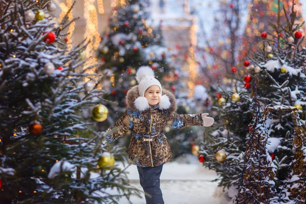 küçük kız açık havada kışın Noel ağaçları arasında ayakta portresi 