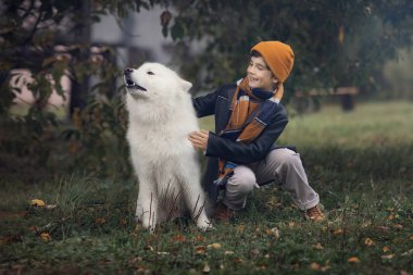 Sonbahar parkta samoyed köpek ile mutlu çocuk 