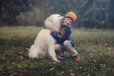 Sonbahar parkta köpek yalamaya gülen çocuk