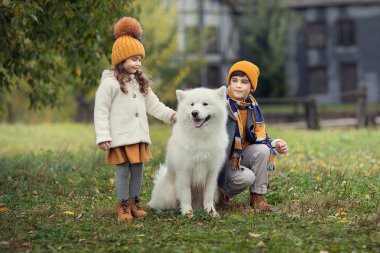 tam uzunlukta atış sonbahar parkta samoyed köpek ile iki çocuk 