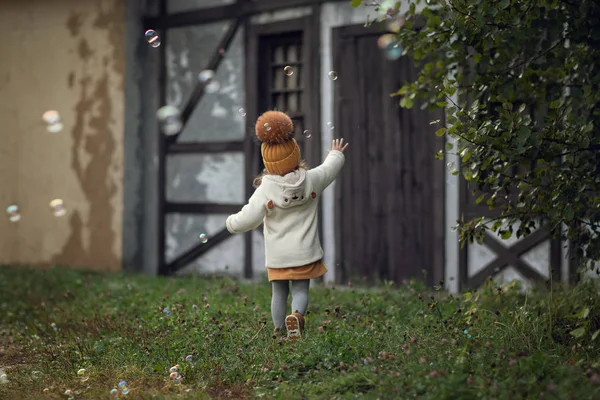 屋外のシャボン玉で遊ぶ少女の背面図 — ストック写真