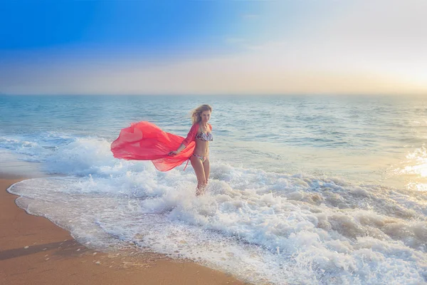 full length of young woman standing in the ocean at sunset